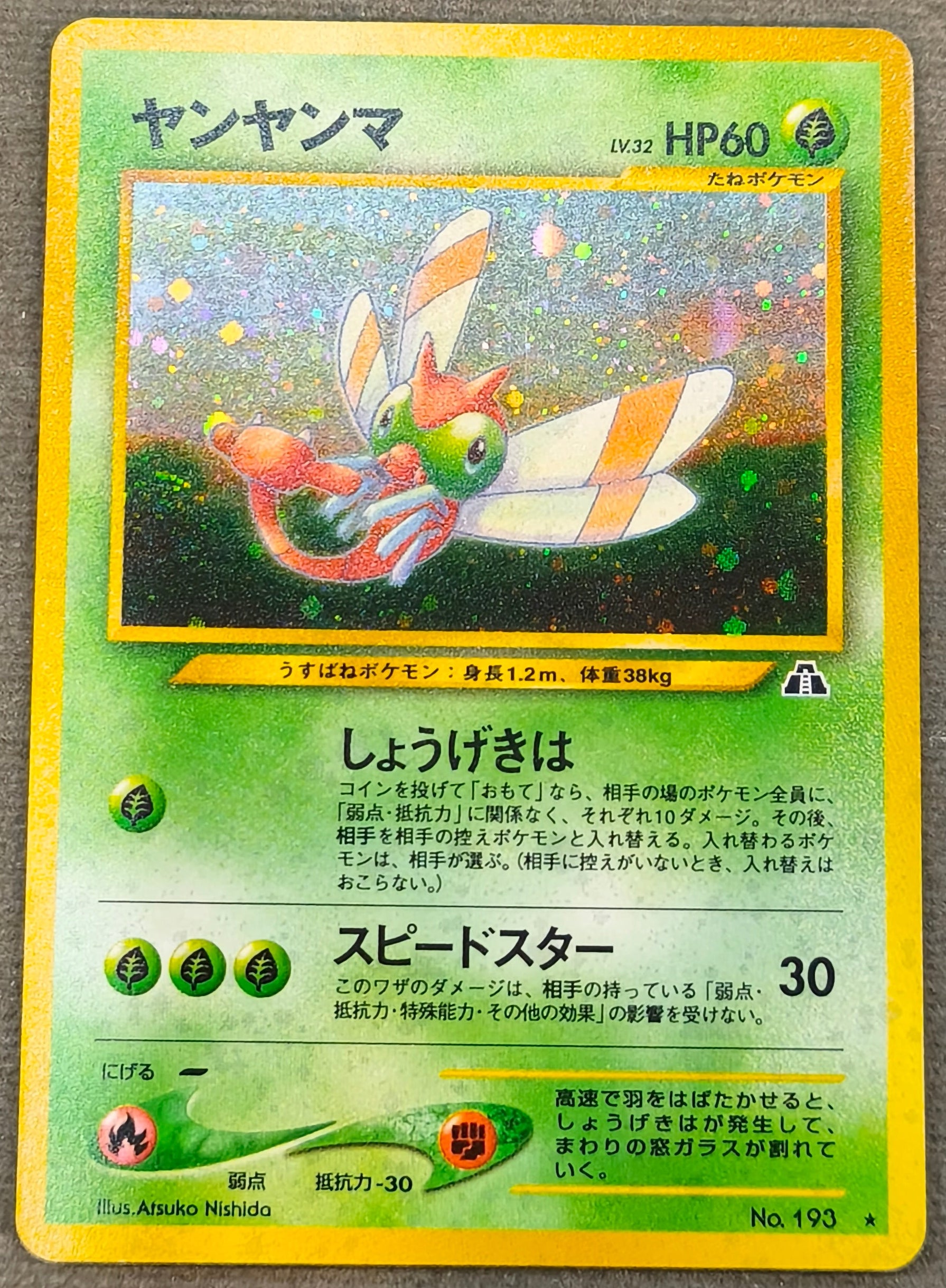 A Japanese Pokémon trading card featuring Yan Yanma, displayed on a gray fabric surface.